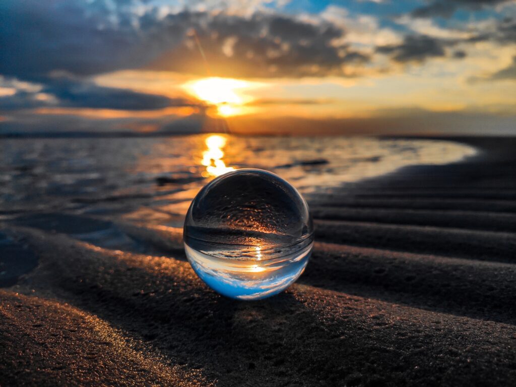 A glass ball on the beach at sunset.